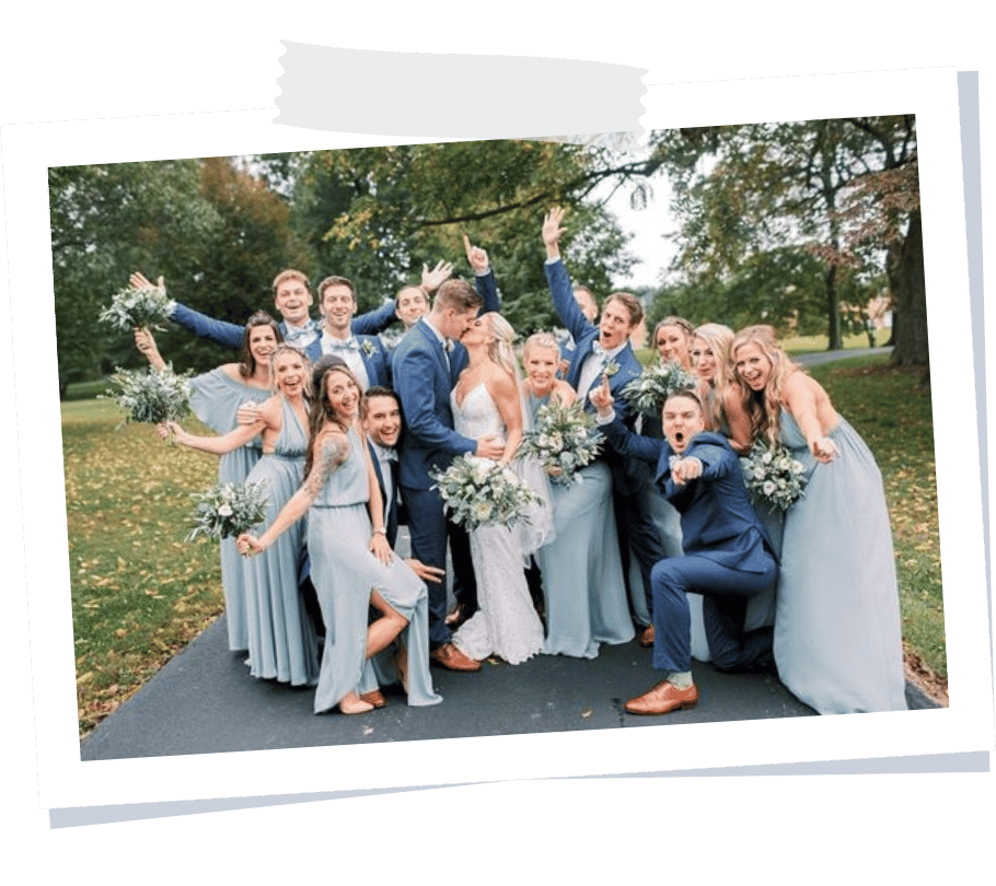 Foto de um grupo de amigos com trajes sociais, em um casamento, posando com os noivos