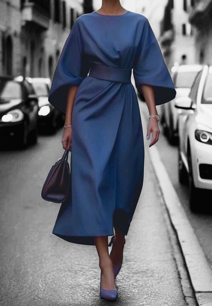 Imagem de uma mulher andando na calçada, com vestido e sapato azuis e bolsa preta